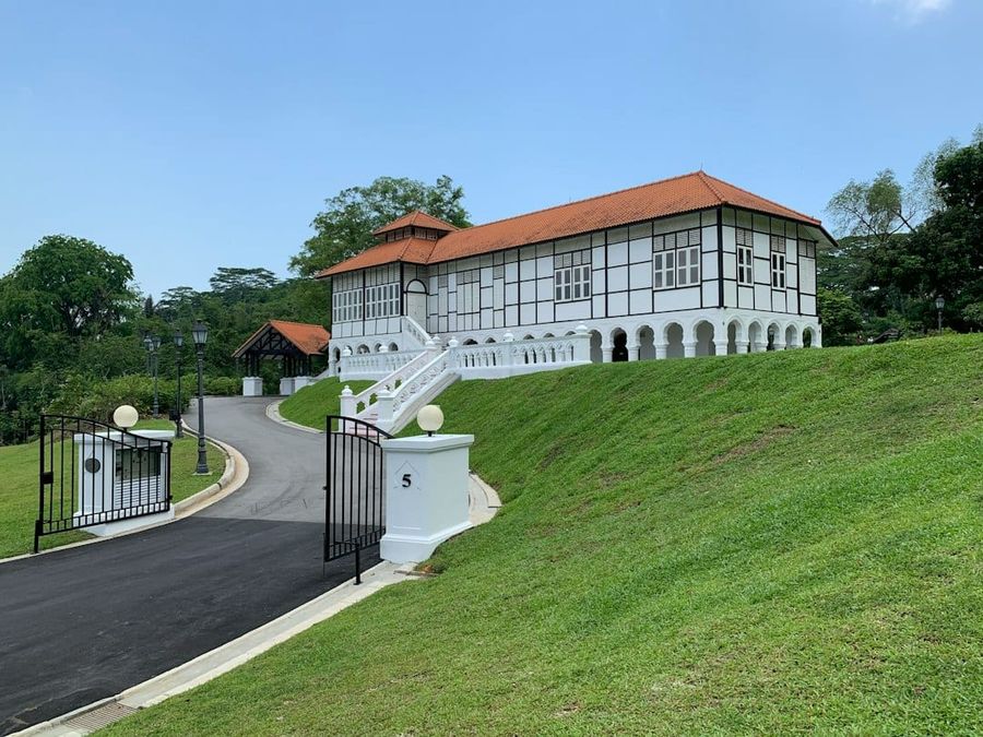 Large white two-storey Singapore landed home with red roof and mature trees